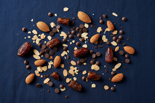 generate an image of whole almonds, almond flakes, dates and milk and dark chocolate chips scattered with a navy background